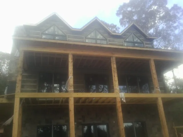 Dormers and porch framing on a large log home under construction — Roof Coating work by our crew in Porter
